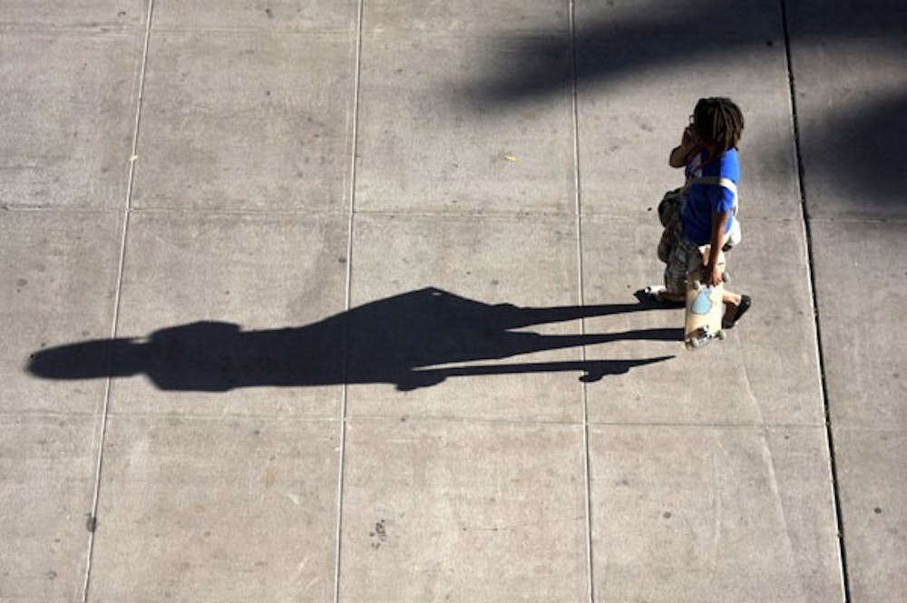 FIVE O'CLOCK SHADOW: As a student walks down Tyler Mall past Old Main, the setting sunlight casts an exact shadow of her figure. (Photo by Scott Stuk)