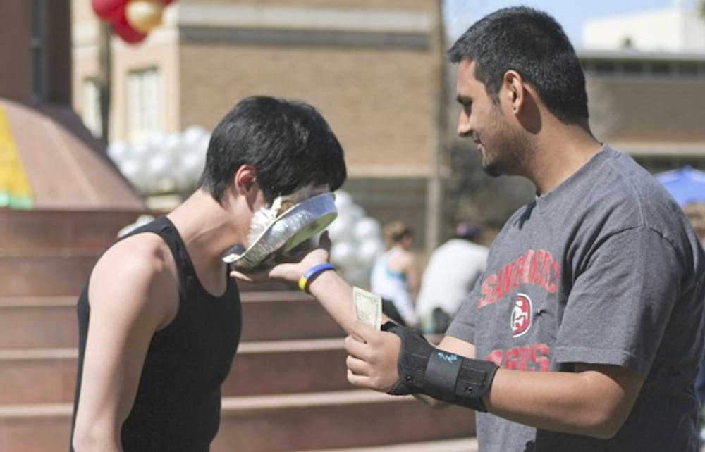 PIE'D FOR A CAUSE: Pi Kappa Phi sophomore Andrew Chang takes a pie in the face from sophomore Gaurav Chibber as part of the fraternity's event on Hayden Lawn Tuesday to raise money and awareness for people with disabilities through their organization "Push America." (Photo by Lisa Bartoli)