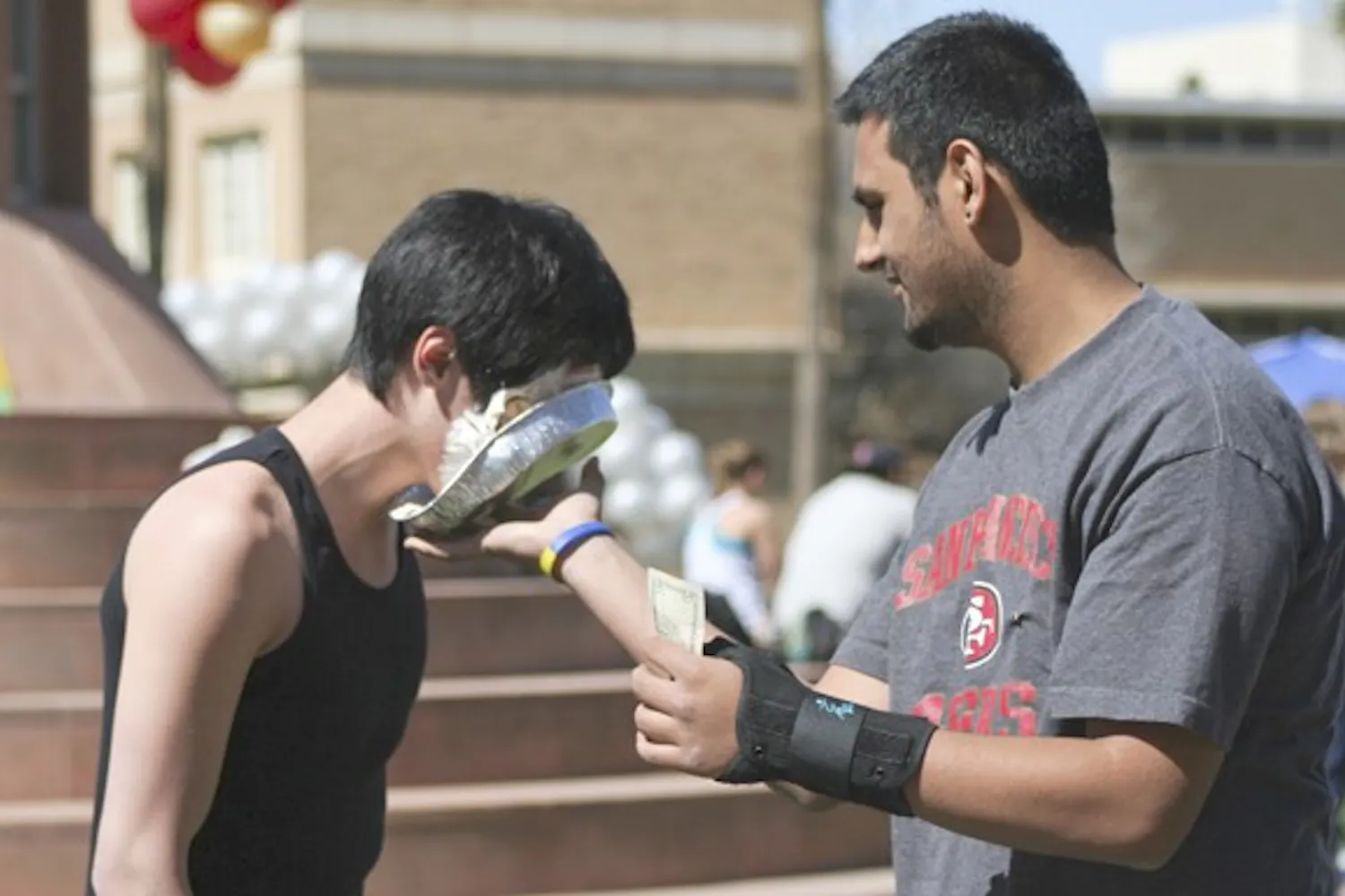 PIE'D FOR A CAUSE: Pi Kappa Phi sophomore Andrew Chang takes a pie in the face from sophomore Gaurav Chibber as part of the fraternity's event on Hayden Lawn Tuesday to raise money and awareness for people with disabilities through their organization "Push America." (Photo by Lisa Bartoli)