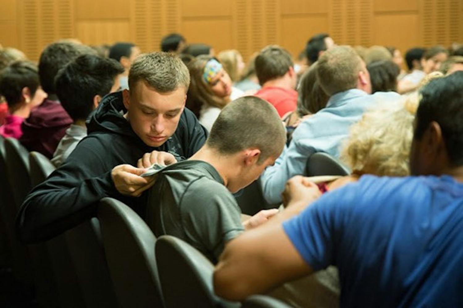 Students turn to one another to see what brands of clothes they are wearing at the beginning of a United Students Against Sweatshops worker tour event. (Photo by Andrew Ybanez)