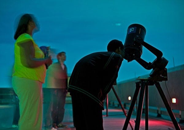 A CLOSER LOOK AT THE STARS: Students enjoy a glimpse of the stars atop the Physical Science building's roof during the monthly Astronomy Open House, hosted by the astronomy and geology graduates of ASU. Telescopes were provided for onlookers to enjoy the wonders of a stormy winter sky. (Photo by Michael Arellano)