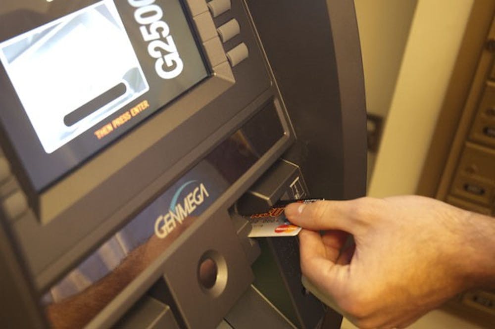 Freshman Jake Gadon quickly removes his Pitchfork Card from a MidFirst Bank ATM before examining available funds. (Photo by Tyler Griffin)