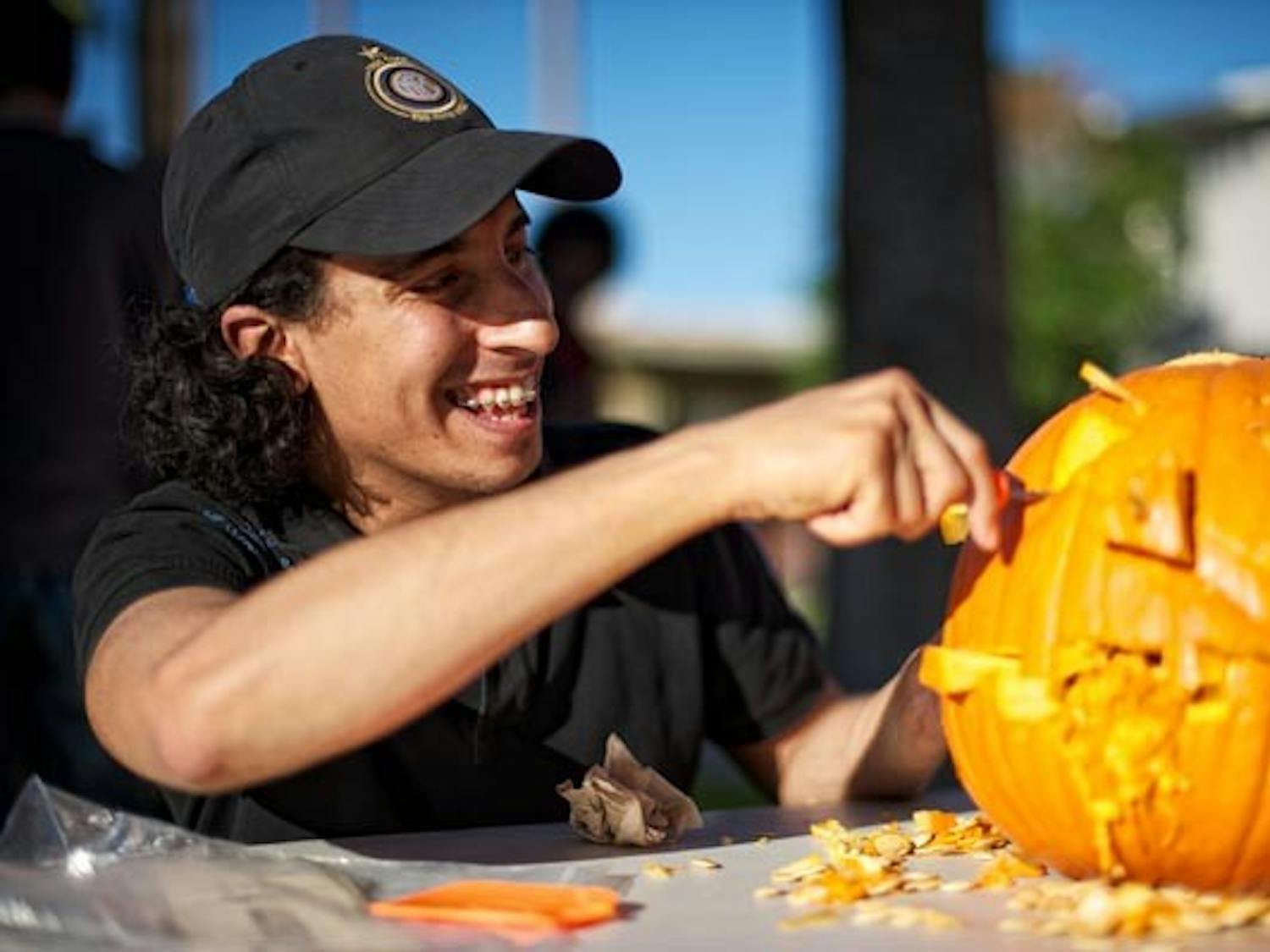FEELS LIKE FALL: Mohammed Al-Bassan, a graduate business student from Saudi Arabia, puts the finishing touches on his Jack-o-Lantern during the AECP's (American English and Culture Program) annual pumpkin carving day on Palm Walk Tuesday afternoon. (Photo by Michael Arellano)