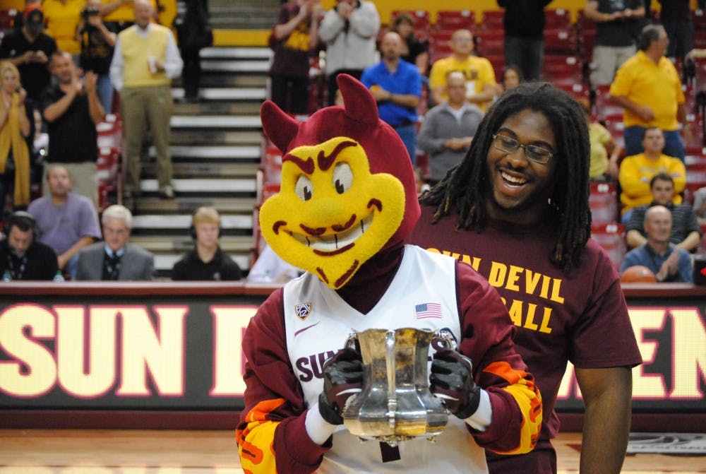 Sparky holds the replica of the Territorial Cup as ASU defensive tackle Will Sutton looks on. The ASU football team presented the cup at the basketball game vs. Arkansas Pine-Bluff on November, 28th 2012. Photo by Nick Krueger