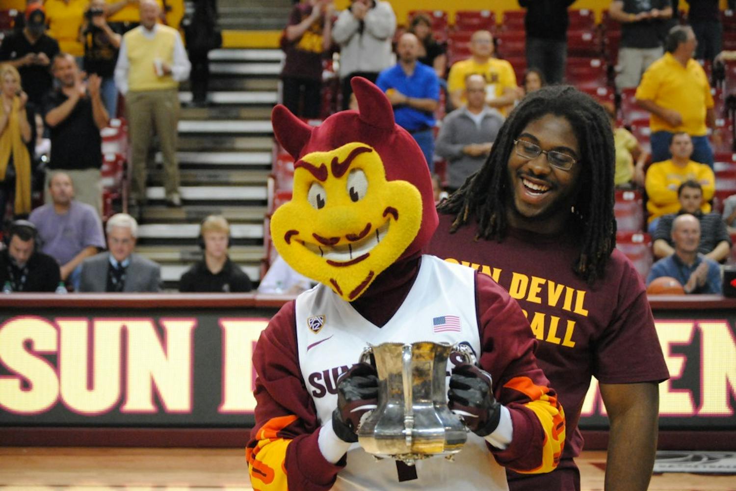 Sparky holds the replica of the Territorial Cup as ASU defensive tackle Will Sutton looks on. The ASU football team presented the cup at the basketball game vs. Arkansas Pine-Bluff on November, 28th 2012. Photo by Nick Krueger