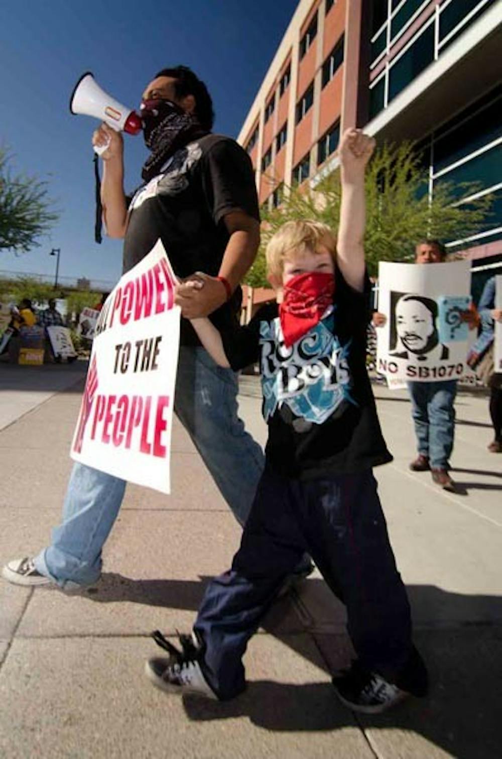 SHOW SUPPORT: Luis Osorio and his son Julian Osorio and many members of Puente, a local immigration rights organization, showed their support outside the Maricopa County Court House Tuesday for those that were arrested Jul. 29 for civil disobedience against SB 1070. (Photo by Aaron Lavinsky)
