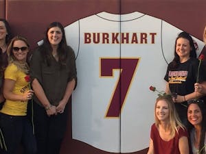 Katie Burkhart, left of the jersey,&nbsp;poses by the Wall of Honor after her number was retired by the ASU softball team on Saturday, April 23, 2016, at Farrington Stadium in Tempe, Arizona. As an collegiate athlete, she had a record of 118-40, an ERA of 1.08 and won the College World Series in 2008.