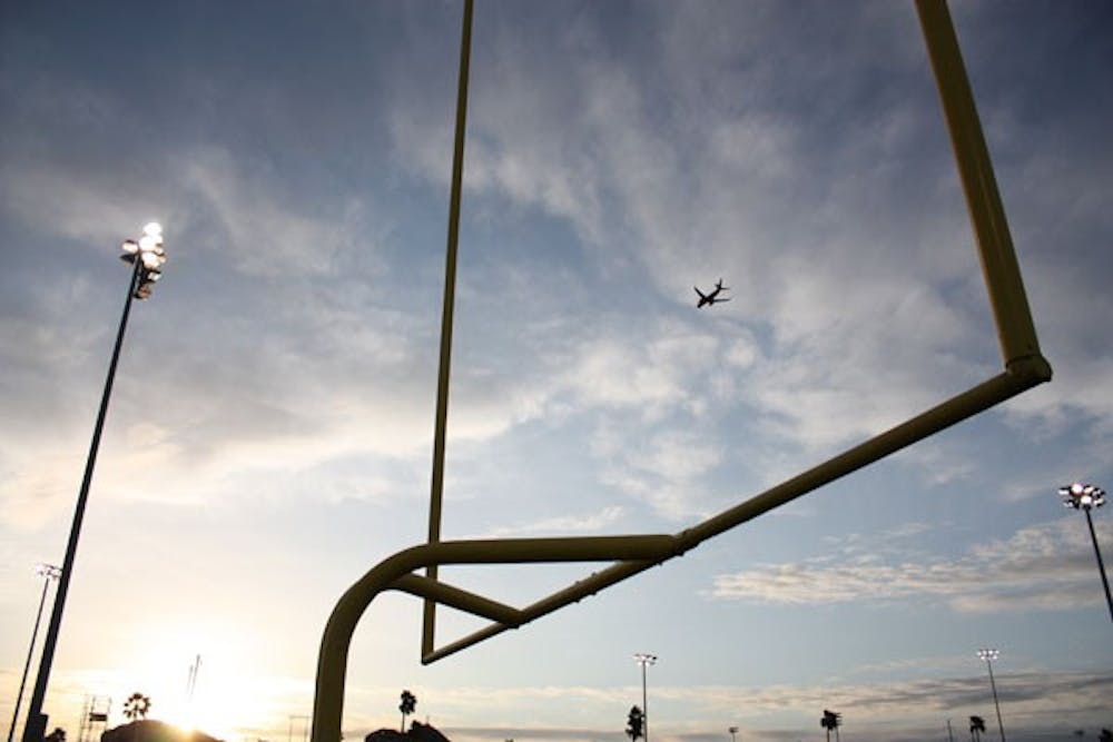 HIGH FLYING: At sunset, a plane flies "through" the field goal on the football practice field during practice last week. (Photo by Kyle Thompson)