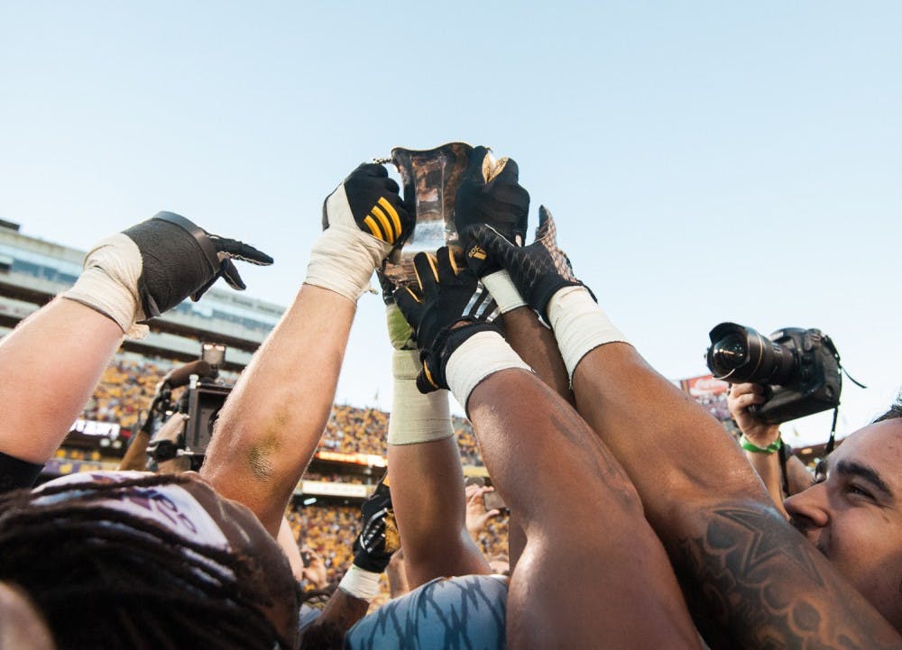 ASU football players lift the Territorial Cup in celebration after defeating UA on Saturday, Nov. 21, 2015, at Sun Devil Stadium in Tempe.