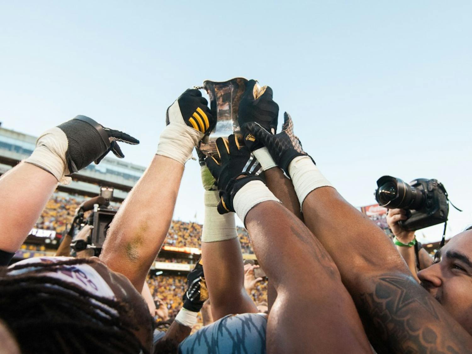 ASU football players lift the Territorial Cup in celebration after defeating UA on Saturday, Nov. 21, 2015, at Sun Devil Stadium in Tempe.