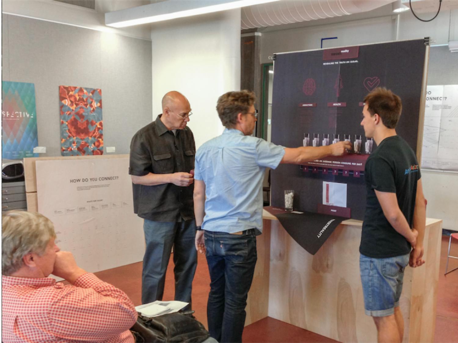Pictured above: Professors Alfred Sanft (left) and Eric Montgomery (right) are critiquing Maxim Golberg’s prototype of his exhibit which aims to inform people about overconsumption of sugar and&nbsp;its harmful effects.