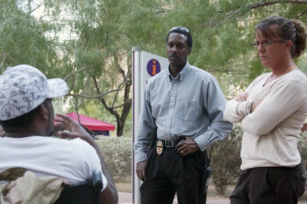 PROTEST COSTS: Left to right, Occupant Daywon Carson, 29, interacts with Phoenix Police Det. Tony Davis and Det. Dottie Conroy on Tuesday at Cesar Chavez Plaza. Since the start of the Occupy movement in Downtown Phoenix, more than $200,000 has been spent on police overtime for the extended enforcement. (Photo by Shawn Raymundo)