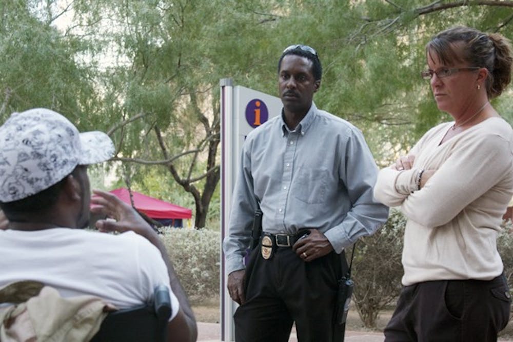 PROTEST COSTS: Left to right, Occupant Daywon Carson, 29, interacts with Phoenix Police Det. Tony Davis and Det. Dottie Conroy on Tuesday at Cesar Chavez Plaza. Since the start of the Occupy movement in Downtown Phoenix, more than $200,000 has been spent on police overtime for the extended enforcement. (Photo by Shawn Raymundo)