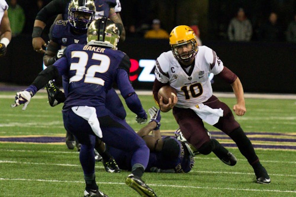 Redshirt senior quarterback Taylor Kelly caries the ball past Washington defenders. Taylor Kelly led ASU to a 24-10 victory against Washington on Oct. 25. (Photo by Andrew Ybanez)