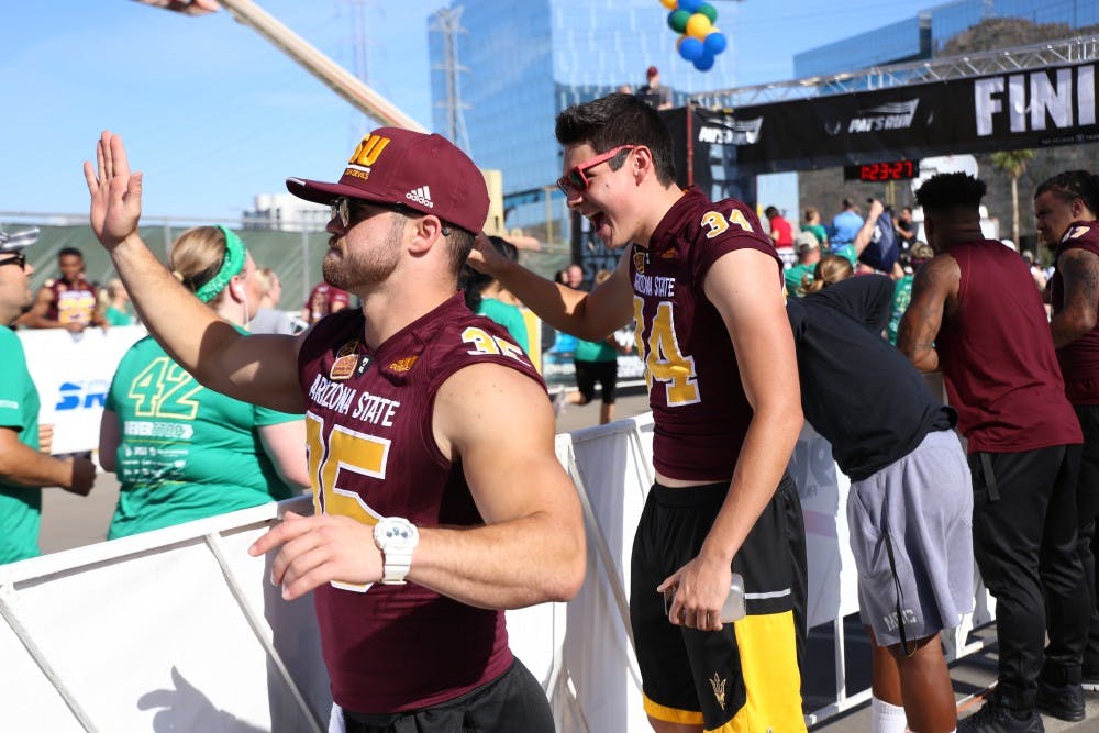 ASU football players high-five Pat's Run participants as they approach the finish line on Saturday, April 23, 2016, in Tempe, Arizona.