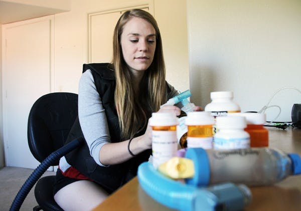 FINDING A CURE: Lauren Meiss, a senior biomedical engineering student diagnosed with cystic fibrosis at three months, wears her physical therapy vest and looks over her daily prescriptions. Meiss was just awarded the $19,000 Abbott CFCareForward scholarship on Oct. 25. (Photo by Rosie Gochnour)