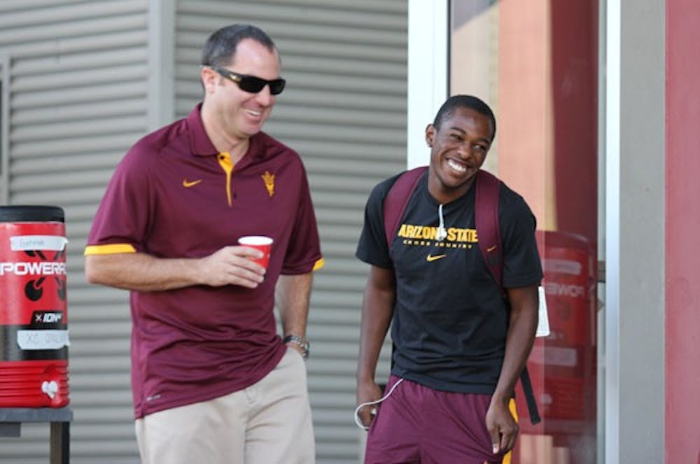 Redshirt senior Darius Terry shares a laugh with men’s coach Louie Quintana during an ASU cross-country practice on Oct. 3. (Photo by Kyle Newman)