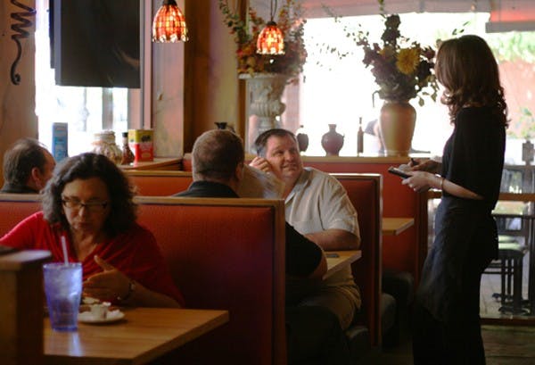 Waitress Kate Rullo takes customer Randy Baker's order Monday during lunch. Baker works nearby and has been waiting for My Big Fat Greek Restaurant to open after the fire occurred. (Photo by Perla Farias)