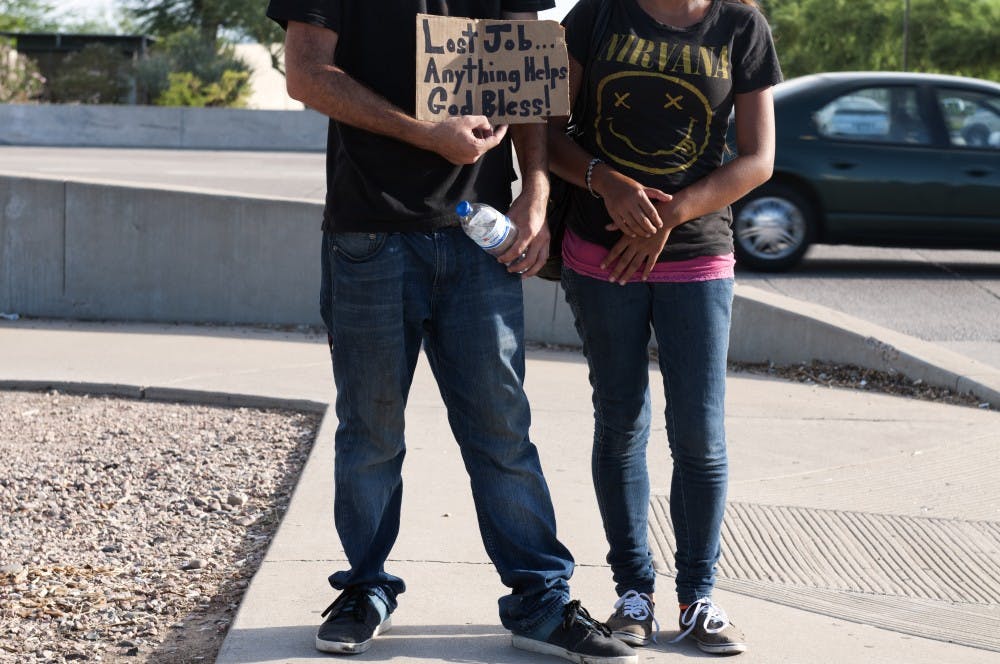 This couple, ages 27 and 23, work as a team, asking for money on the off-ramp of the 101 and Broadway Road to support their four-year-old daughter, after medical bills left the family in a bind. The family turned to panhandling after recently losing their jobs, home and vehicle, but hope it doesn't last long. (Photo by Mario Mendez)