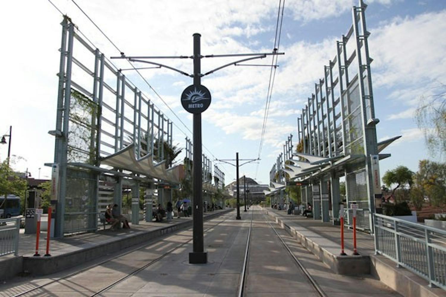 CROSSING THE TRACKS: People wait on the benches at the Rural Road Light Rail stop Wednesday afternoon. (Photo by Nikolai De Vera)