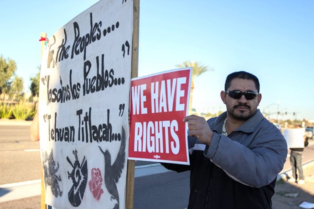 Jose Lopez Holds a sign and a banner on Glendale Avenue and the 101 at a protest against the Mexican Soccer Federation's decision to hold their match against Denmark in Phoenix. Lopez was there with the Barrio Defense Committee. (Photo by Dominic Valente)