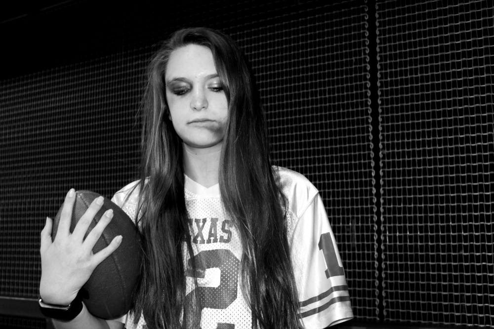 Freshman journalism student Maddie Arnold poses with fake bruises, a jersey and a football in a photo illustration on Sunday, Jan. 29, 2017.