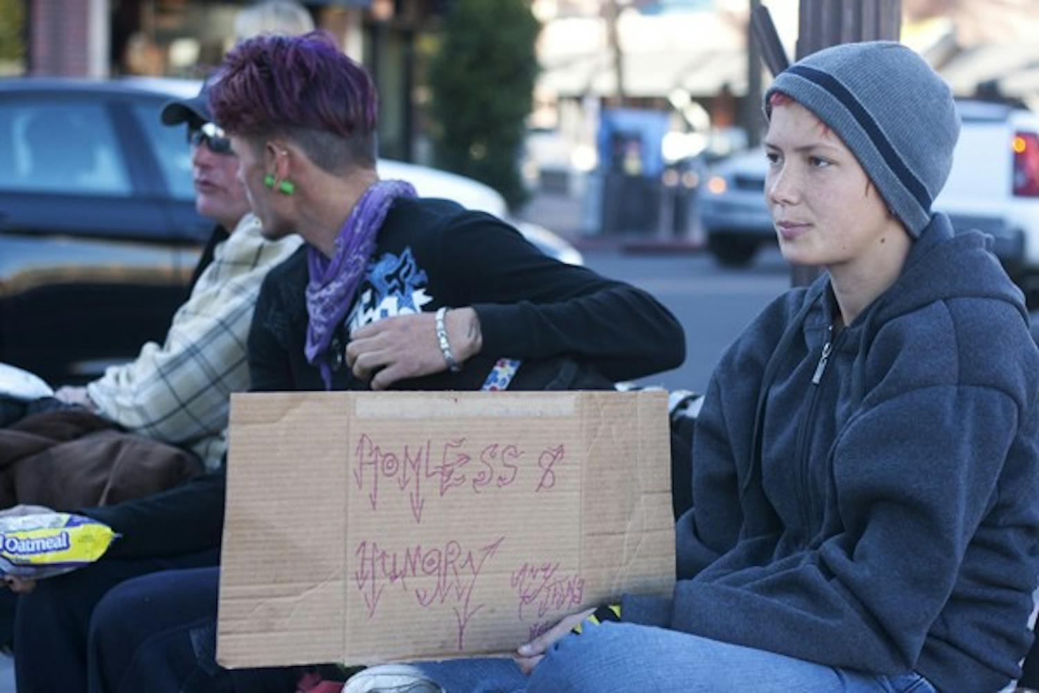 Sugar Girl sits with Eric Super Man and Pony Boy, holding up a sign that says "Homeless & Hungry" on Mill Avenue Monday afternoon. (Photo by Perla Farias)