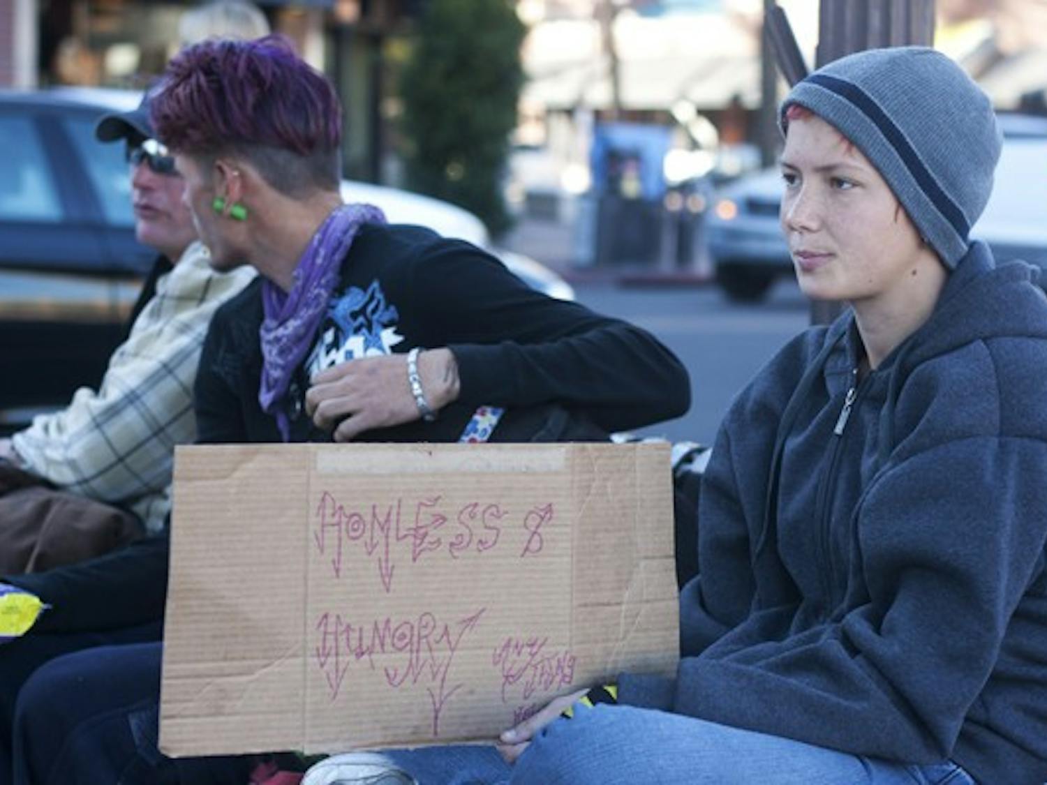 Sugar Girl sits with Eric Super Man and Pony Boy, holding up a sign that says "Homeless & Hungry" on Mill Avenue Monday afternoon. (Photo by Perla Farias)