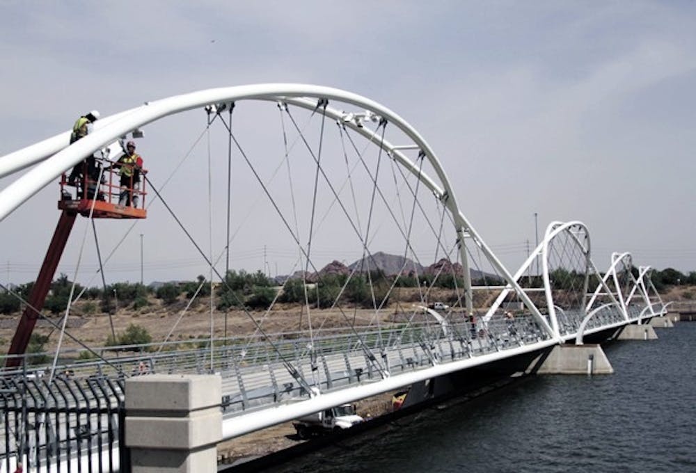 CROSSING OVER: Construction workers assemble the new pedestrian bridge crossing Tempe Town Lake on Aug. 19.  The bridge is estimated to be completed later this fall. (Photo by Lisa Bartoli)