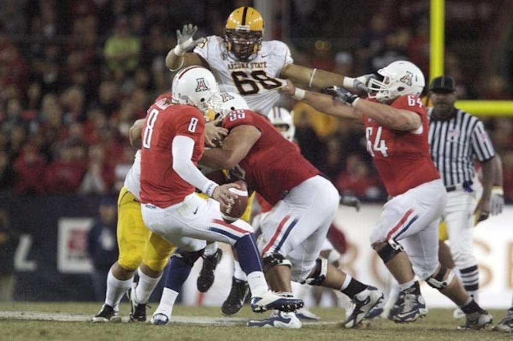 UNDER PRESSURE: UA junior quarterback Nick Foles tries to stay on his feet as ASU defenders move in. The Wildcats had a chance to win late in the fourth quarter, but a blocked extra point sent the game to overtime, where the Sun Devils took a 30-29 victory. (Photo by Scott Stuk)