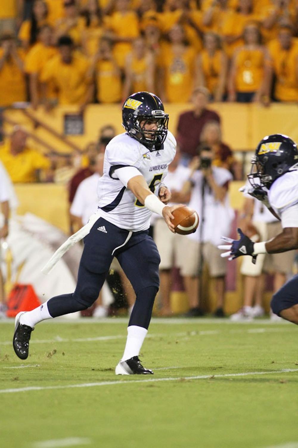 NAU senior quarterback Cary Grossart hands the ball off to junior running back Zach Bauman during NAU’s 63-6 loss to ASU on Thursday. Both of Lumberjacks’ impact players had suffered game-ending injuries in the first half. (Photo by Sam Rosenbaum)
