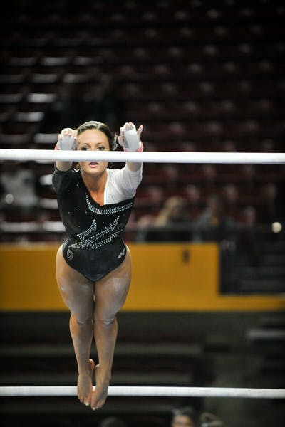 Senior Brianna Gades reaches for the bar during a routine on Jan. 9, 2015 at Sun Devil Stadium. (Photo by Andrew Ybanez)
