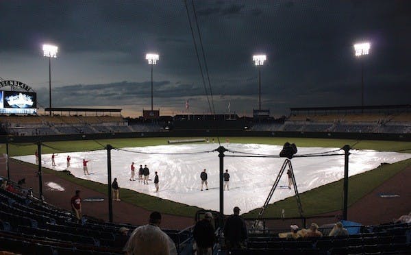 RAIN, RAIN, GO AWAY: Stadium crews spent plenty of time on the field during more than six hours of rain delays on Sunday. (Photo by Nick Kosmider