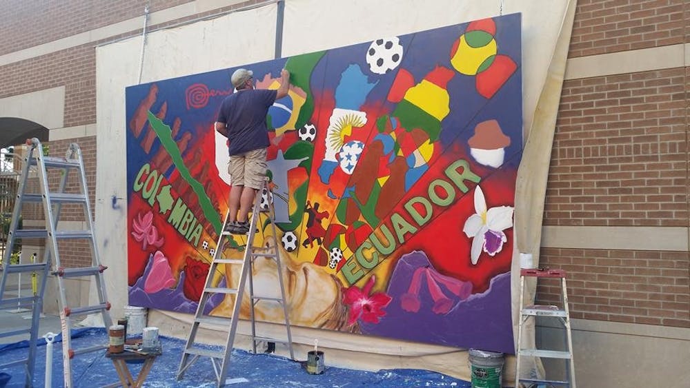 Local artist Hugo Medina&nbsp;works on the mural he designed for last year's&nbsp;Hispanic Heritage Month on Oct. 2, 2015. The mural is hanging on the West campus for this year's celebration as well.