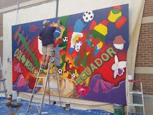 Local artist Hugo Medina&nbsp;works on the mural he designed for last year's&nbsp;Hispanic Heritage Month on Oct. 2, 2015. The mural is hanging on the West campus for this year's celebration as well.