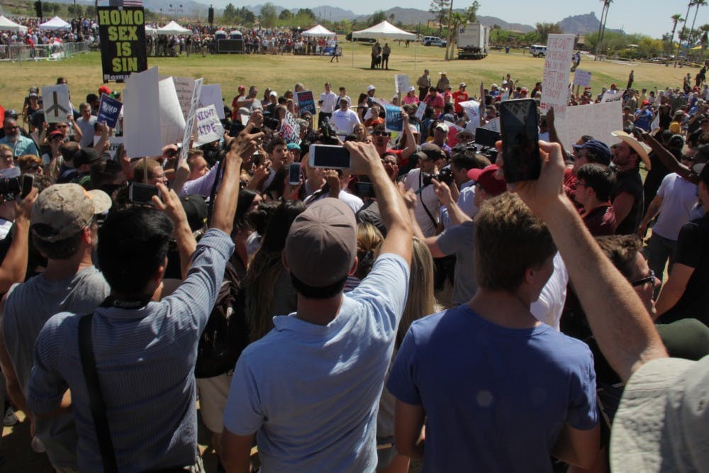 A crowd forms around Trump supporters and protestors exchanging verbal insults.