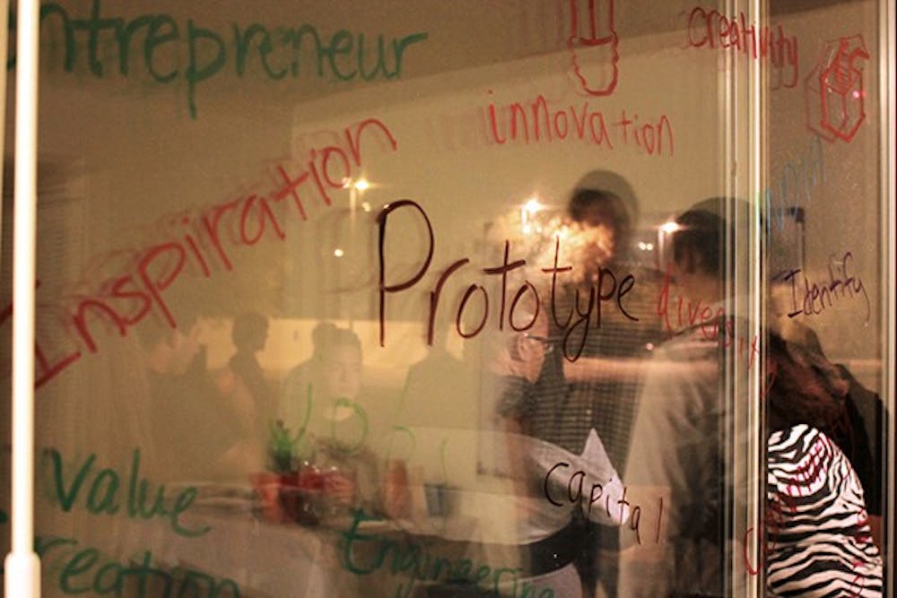 Student entrepreneurs mark up a glass door with Sharpie with values that they find important at the Startup Village. (Photo by Shiva Balasubramanian)