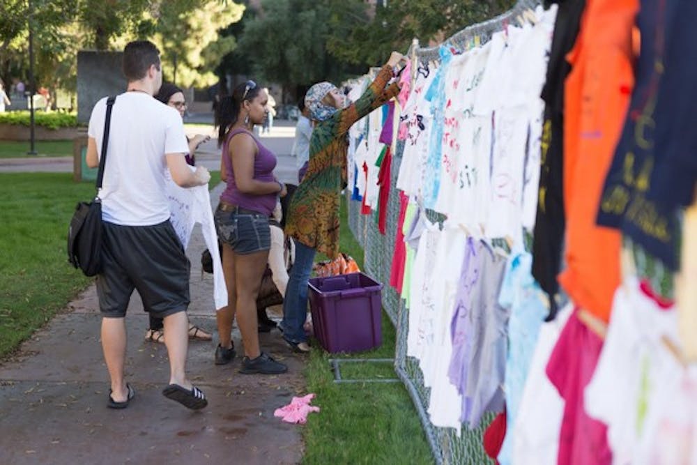 ASU students take part in putting up their messages on t-shirts for the Clothesline Project during Domestic Violence Awareness Month at Hayden Lawn. The Clothesline Project will be a visual display of shirts with graphic messages and illustrations designed by survivors, family, friends, children, and anyone else impacted by gender-based violence. (Photo by Ryan Liu)