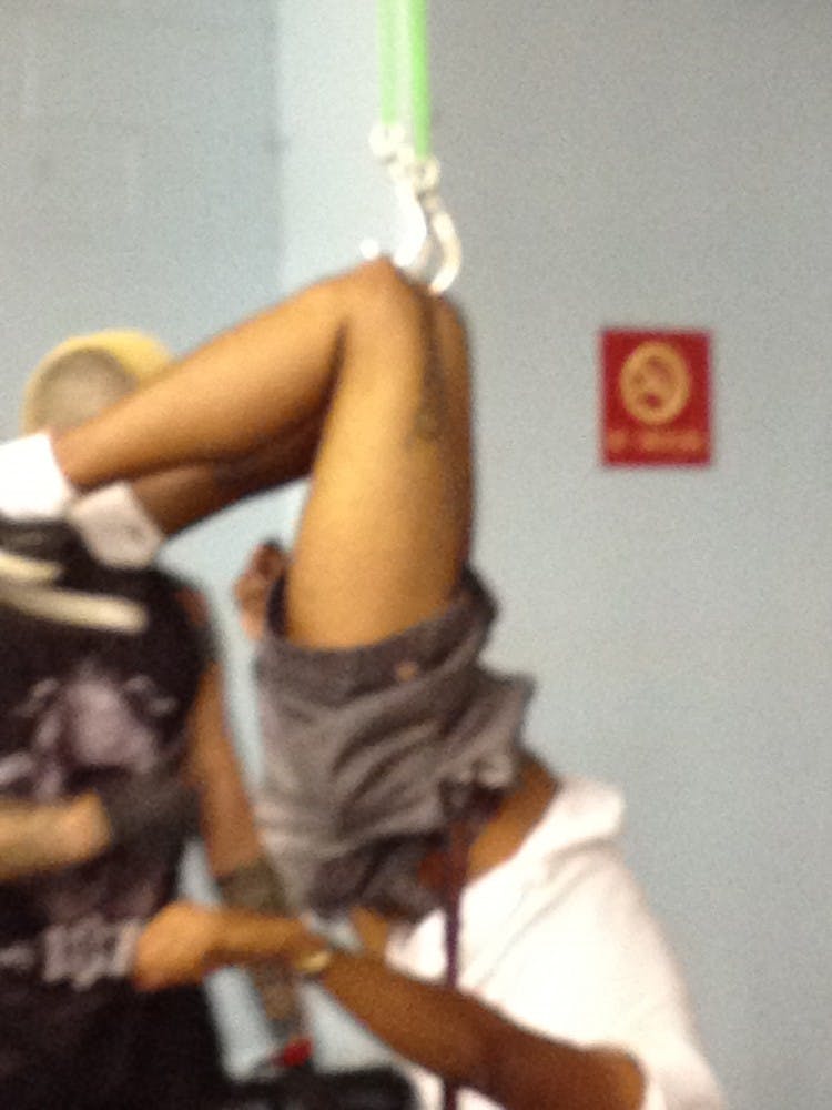 A man's body is suspended at the knees by metal hooks. Photo by Alec Damiano.