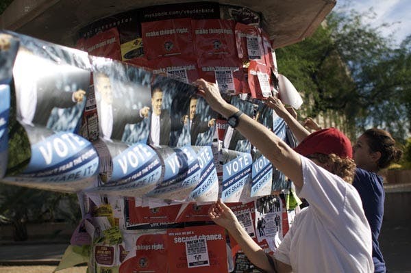 GO VOTE: Marilyn Kinnier (left) and political science senior Sabrina Garibovic, who are volunteers of Organizing for America, hang posters around the Tempe campus Sunday to encourage students to vote.&nbsp;