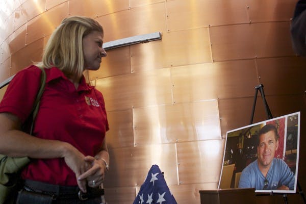IN MOURNING: Christine Connors views a photo of Tempe Police Det. Tim Barber, who passed away at the age of 42 from prostate cancer. Friends, family and fellow police officers attended a small reception for Barber on Tuesday. (Photo by Shawn Raymundo)