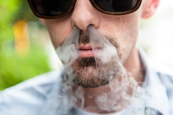 History junior Jared Pitts exhales vapor from his electronic cigarette, Tuesday, Dec. 2, 2014 at CityScape in downtown Phoenix. Proponents of e-cigarettes say they are a healthier alternative to conventional tobacco products, but critics warn that they may have dangerous side effects. (Photo by Ben Moffat)