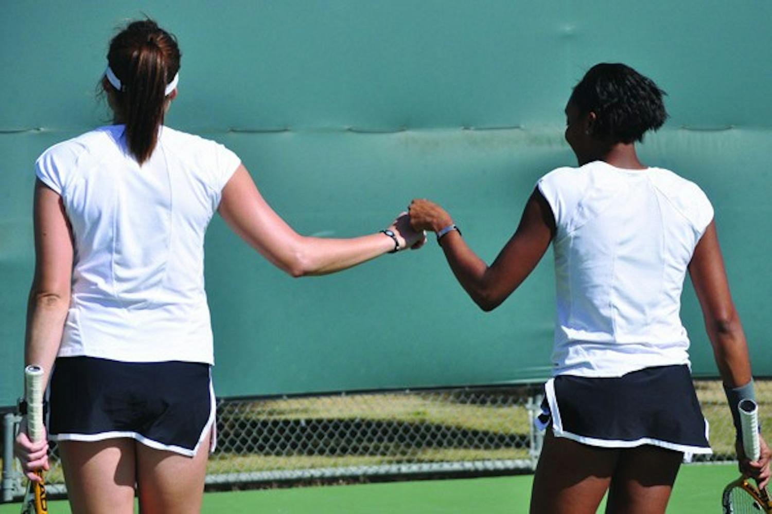 Day-to-day: Undefeated doubles pair senior Ashlee Brown (left) and junior Sianna Simmons bump fists after a point. The Sun Devils are hoping to have senior Kelcy McKenna and junior Michelle Brycki healthy for this weekend’s duals after the pair missed matches last week. (Photo by Sierra Smith)