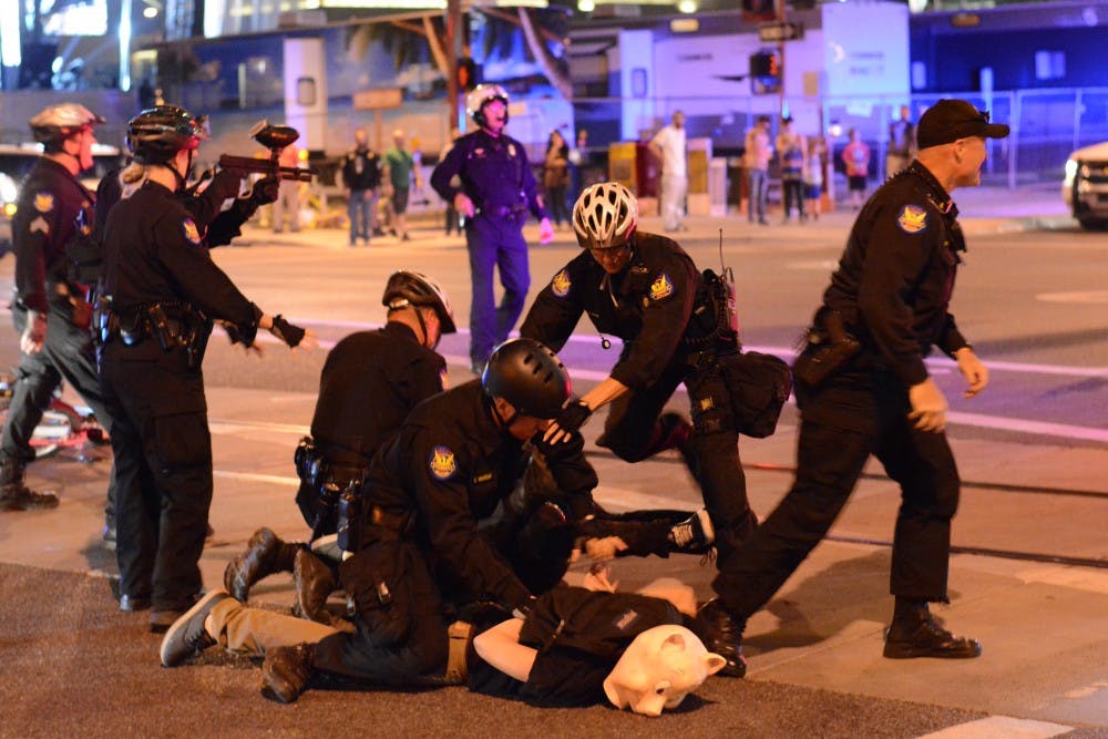 Police apprehend a protestor on Saturday night at Washington and First Street during the Downtown Zombie Walk on Saturday, Oct. 25, 2014.Wearing a pig mask, several police officers subdue the protestor. (Photo by Jonathan Williams)