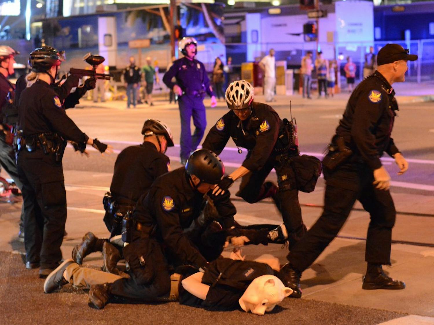 Police apprehend a protestor on Saturday night at Washington and First Street during the Downtown Zombie Walk on Saturday, Oct. 25, 2014.Wearing a pig mask, several police officers subdue the protestor. (Photo by Jonathan Williams)