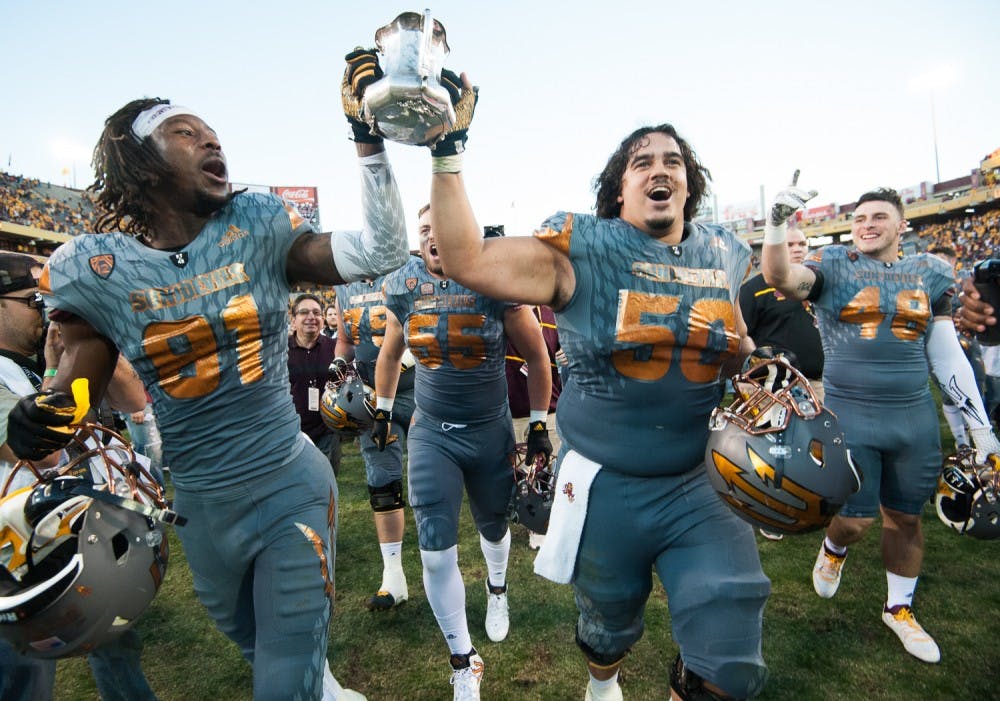 Redshirt senior wide receiver Gary Chambers (81) and senior offensive lineman Nick Kelly (50) carry the Territorial Cup off the field after defeating UA on Saturday, Nov. 21, 2015, at Sun Devil Stadium in Tempe.