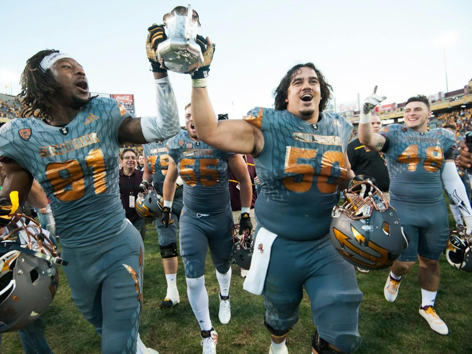Redshirt senior wide receiver Gary Chambers (81) and senior offensive lineman Nick Kelly (50) carry the Territorial Cup off the field after defeating UA on Saturday, Nov. 21, 2015, at Sun Devil Stadium in Tempe.