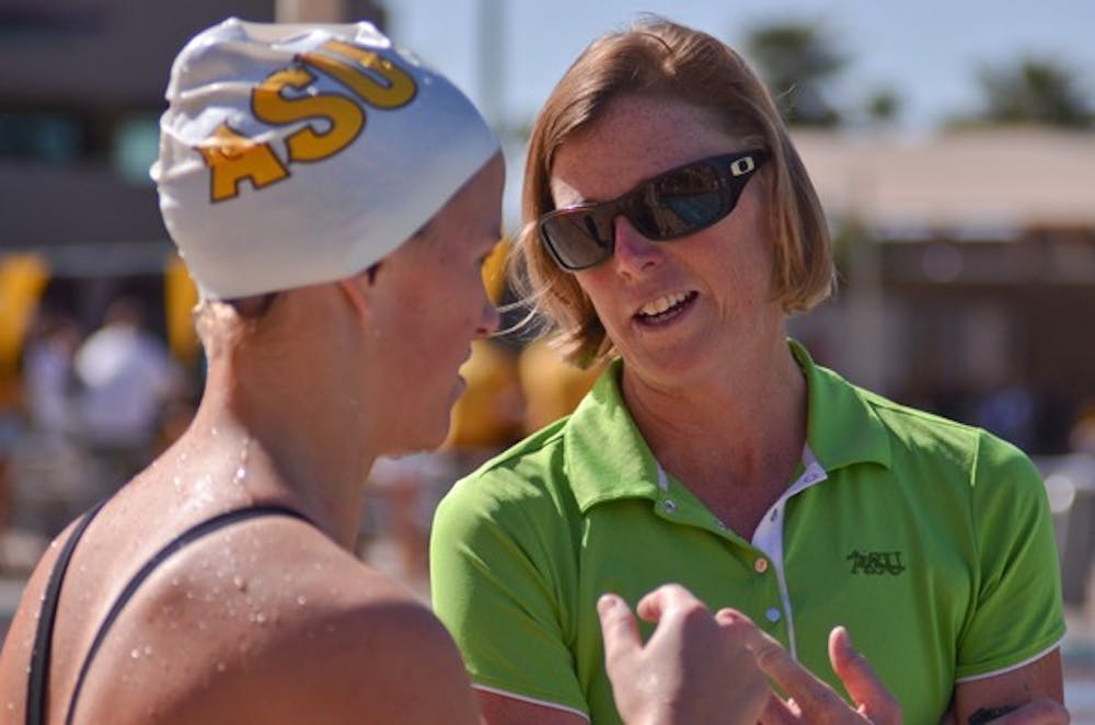 Swim coach Dorsey Tierney-Walker talks strategy with her swimmer before a race during the Sun Devils’ meet against UA on Feb. 11. (Photo by Aaron Lavinsky)
