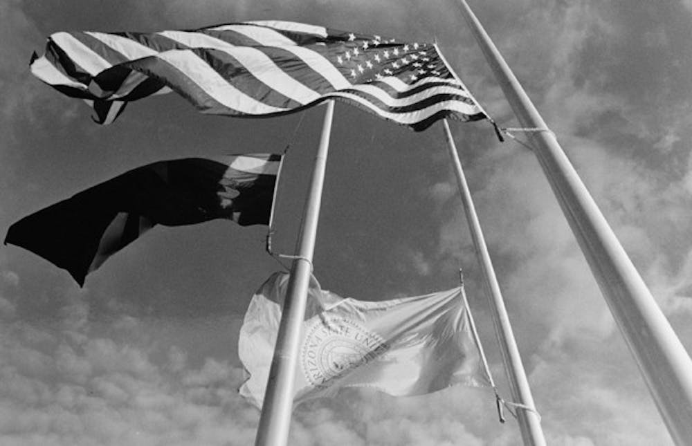 FLYING LOW: Flags at Sun Devil Stadium fly half-mast on Aug. 27, 1990 for a University of Arizona officer who was killed. (Photo by Tamara Wofford)