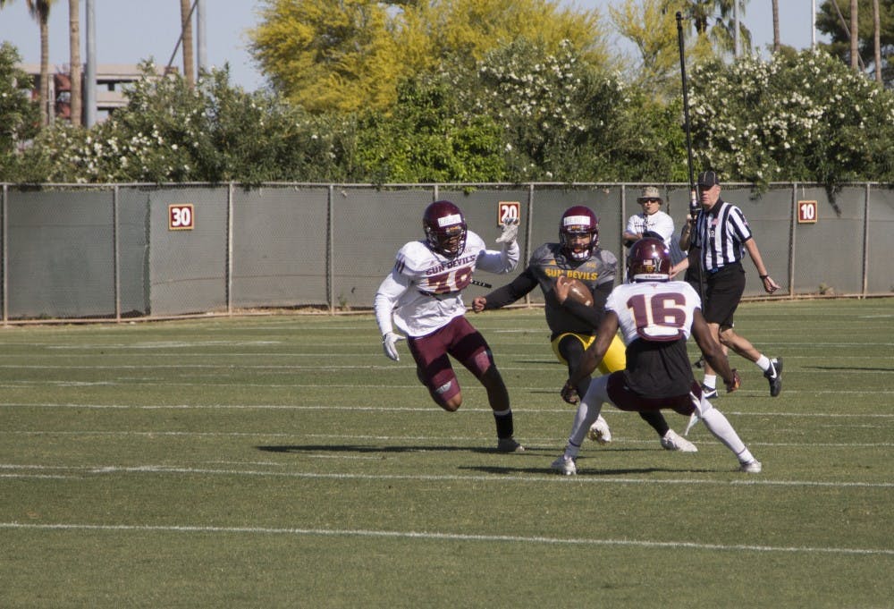 Quarterback Manny Wilkins (5) evades defenders during a scrimmage at Friday's practice. 25 March 2016